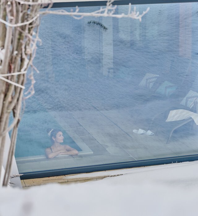 Woman watches the mountains from the indoor pool | © Mathias Lixl